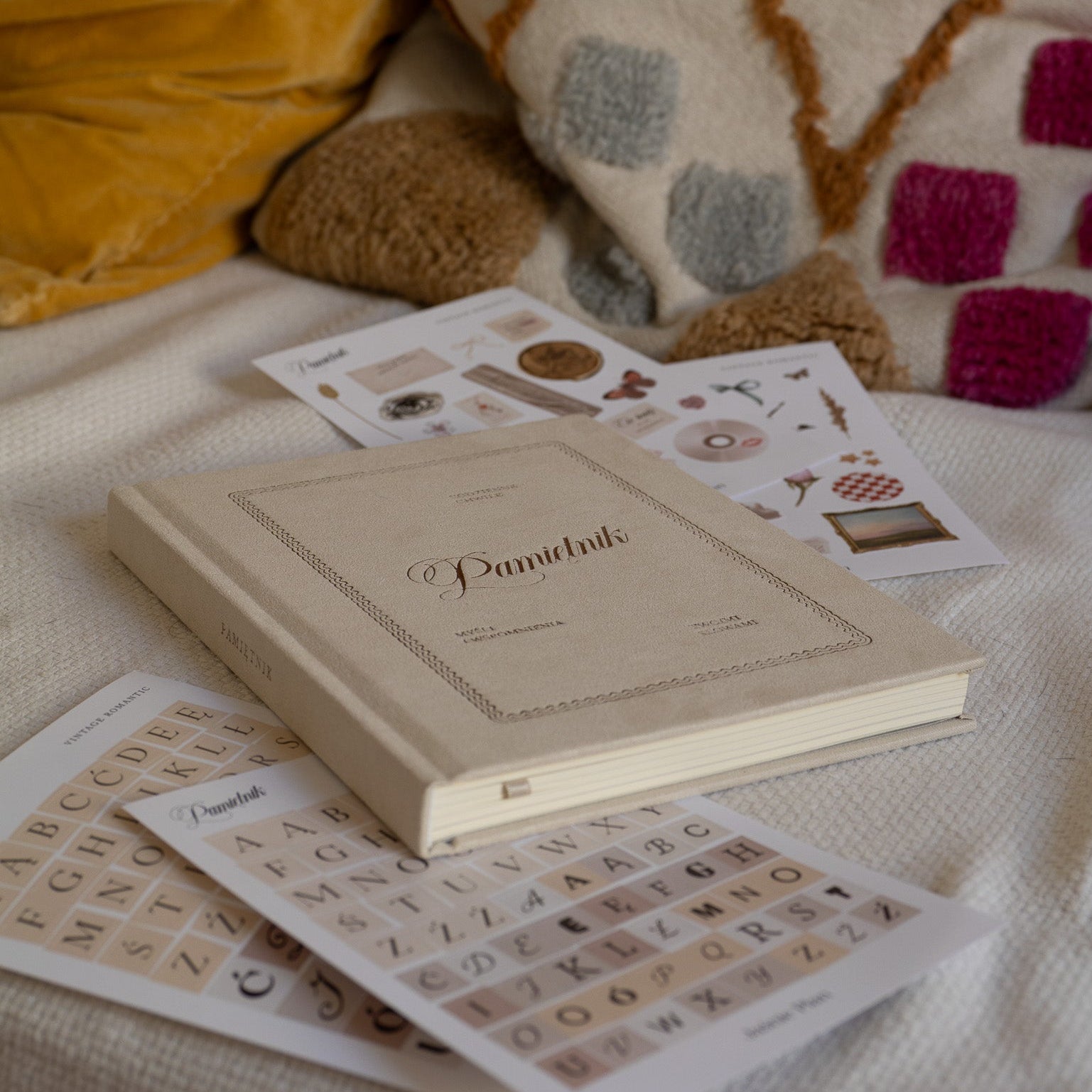 Beżowy pamiętnik na łóżku z naklejkami porozrzucanymi dookoła