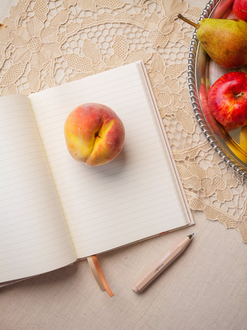 Jabłko leżące na otwartym notesie sielskim