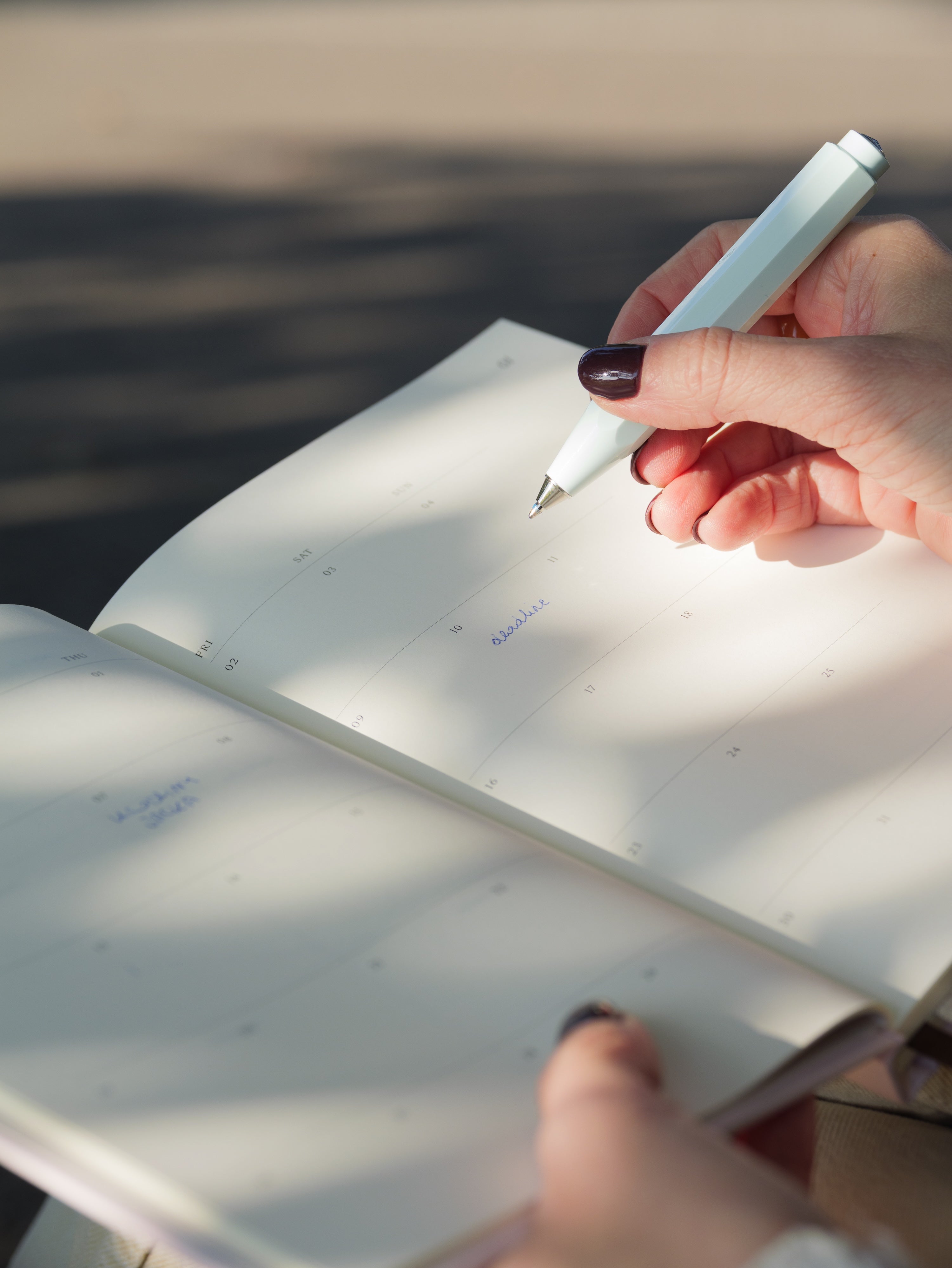 Zbliżenie na dłonie kobiety piszącej w kalendarzu