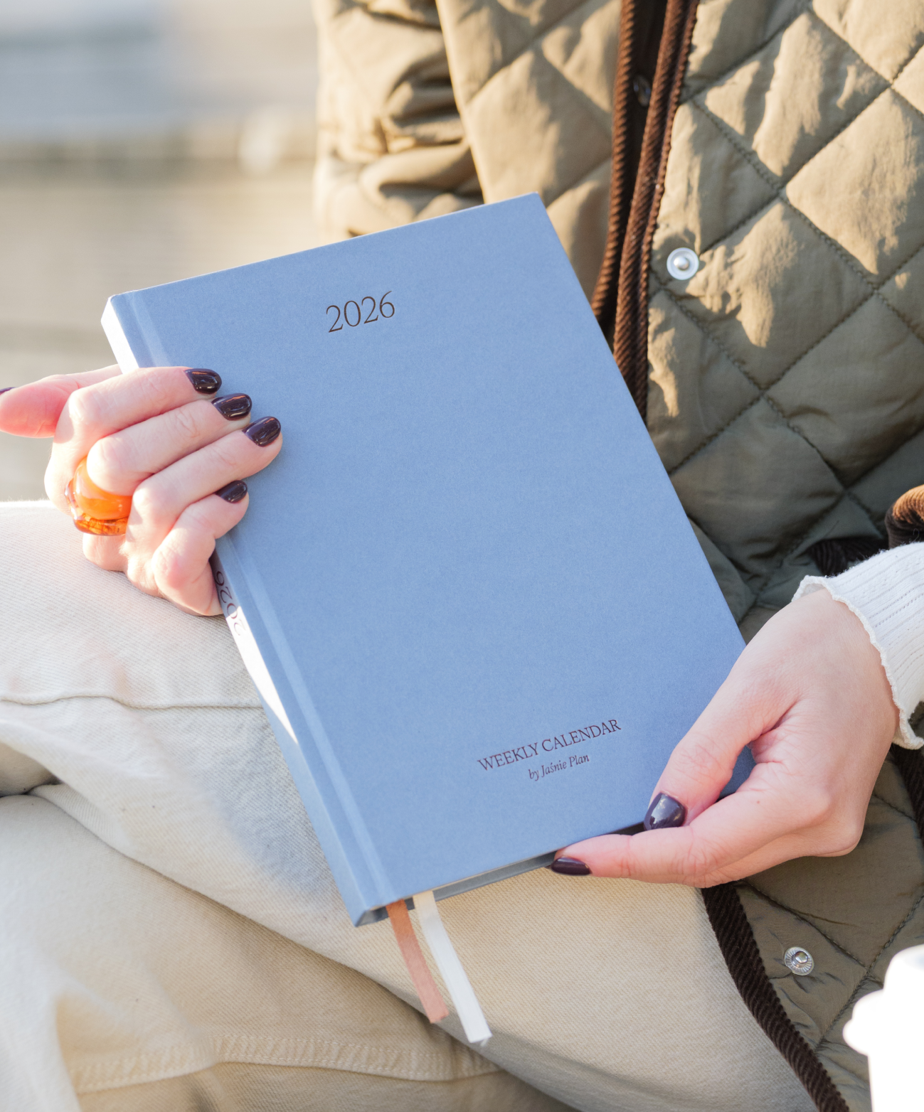 Kobieta prezentująca niebieski Kalendarz 2026 Jaśnie Planu