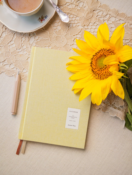 Notes Słonecznikowy leżący na stole, częściowo przykryty słonecznikiem